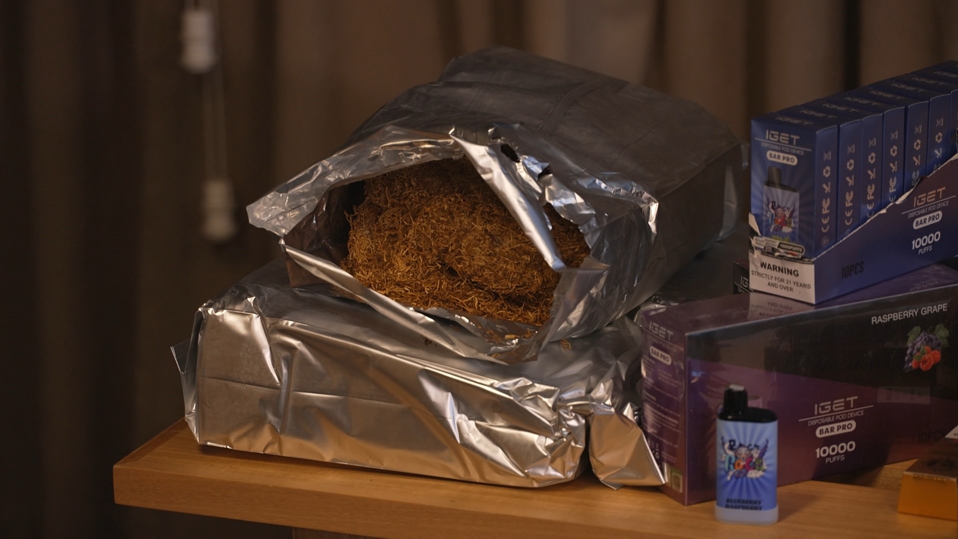 Um saco aberto de tabaco solto ao lado de uma pequena caixa de vaporizadores.