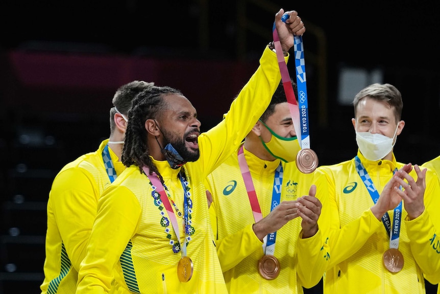 Patty Mills holds his bronze medal in the air at the Tokyo Olympics men's basketball medal ceremony.