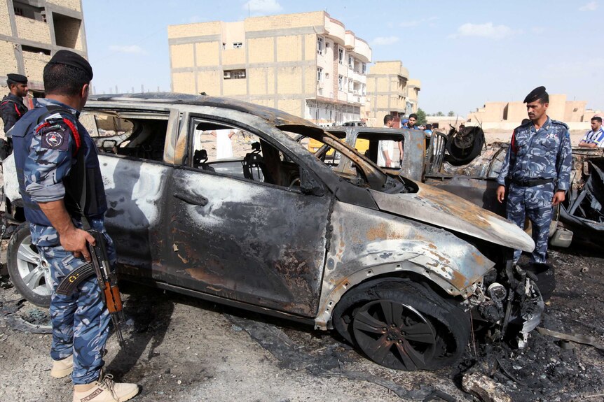Policemen inspect burnt out cars at the site of a bomb attack.