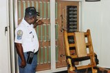 A man in a uniform standing next to an electric chair