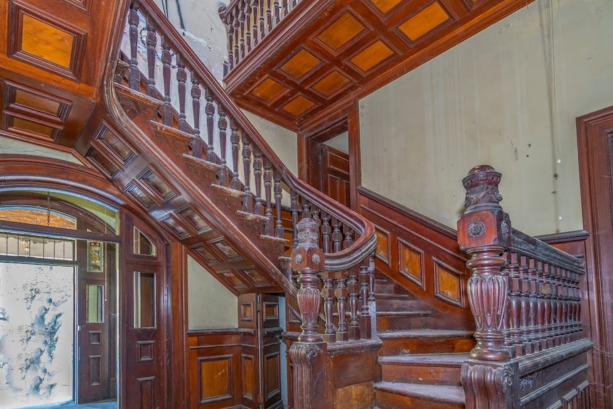 A grand timber stair case with wooden panelling and archways.
