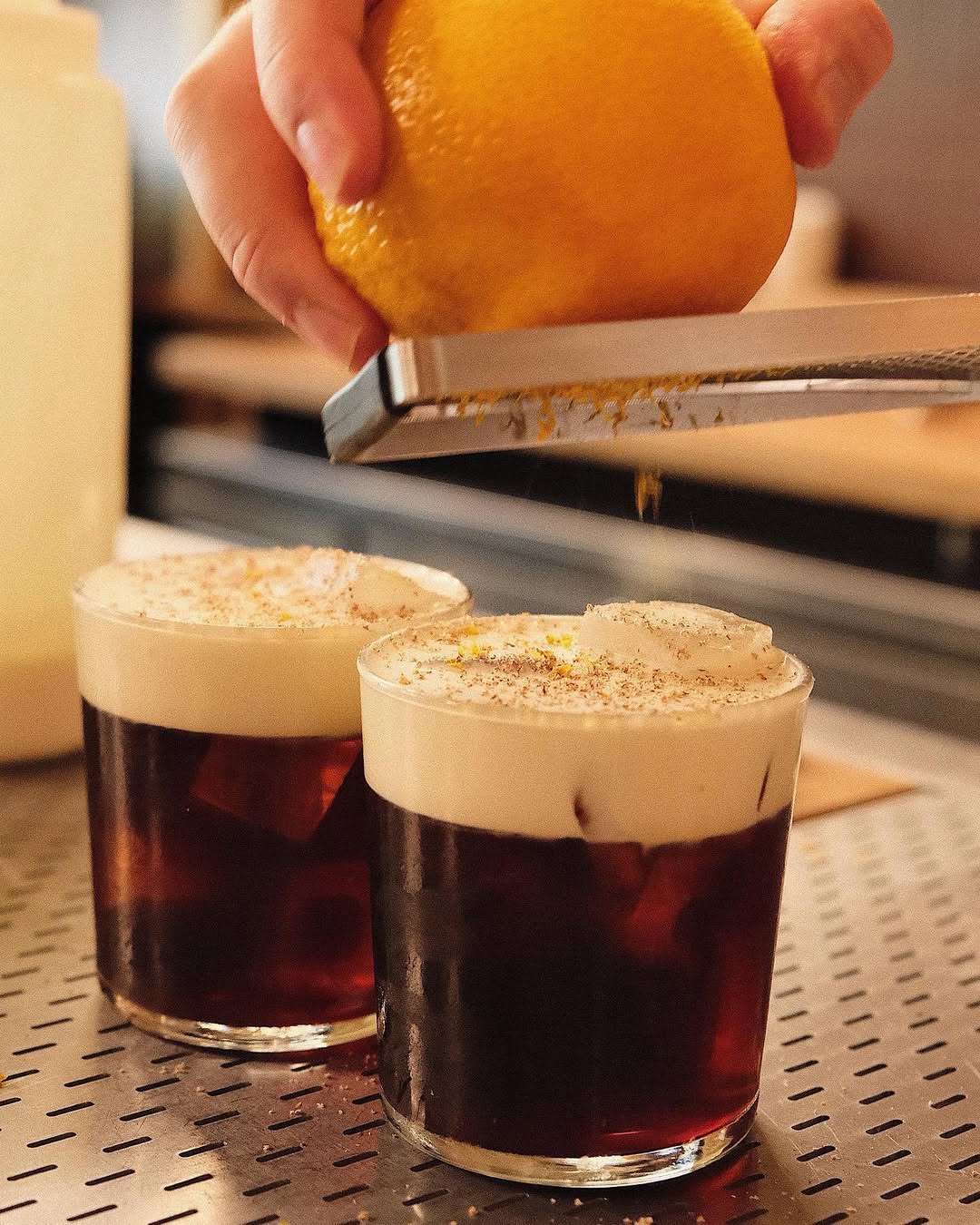 Dos tazas de café con cáscara de naranja cayendo sobre ellas.