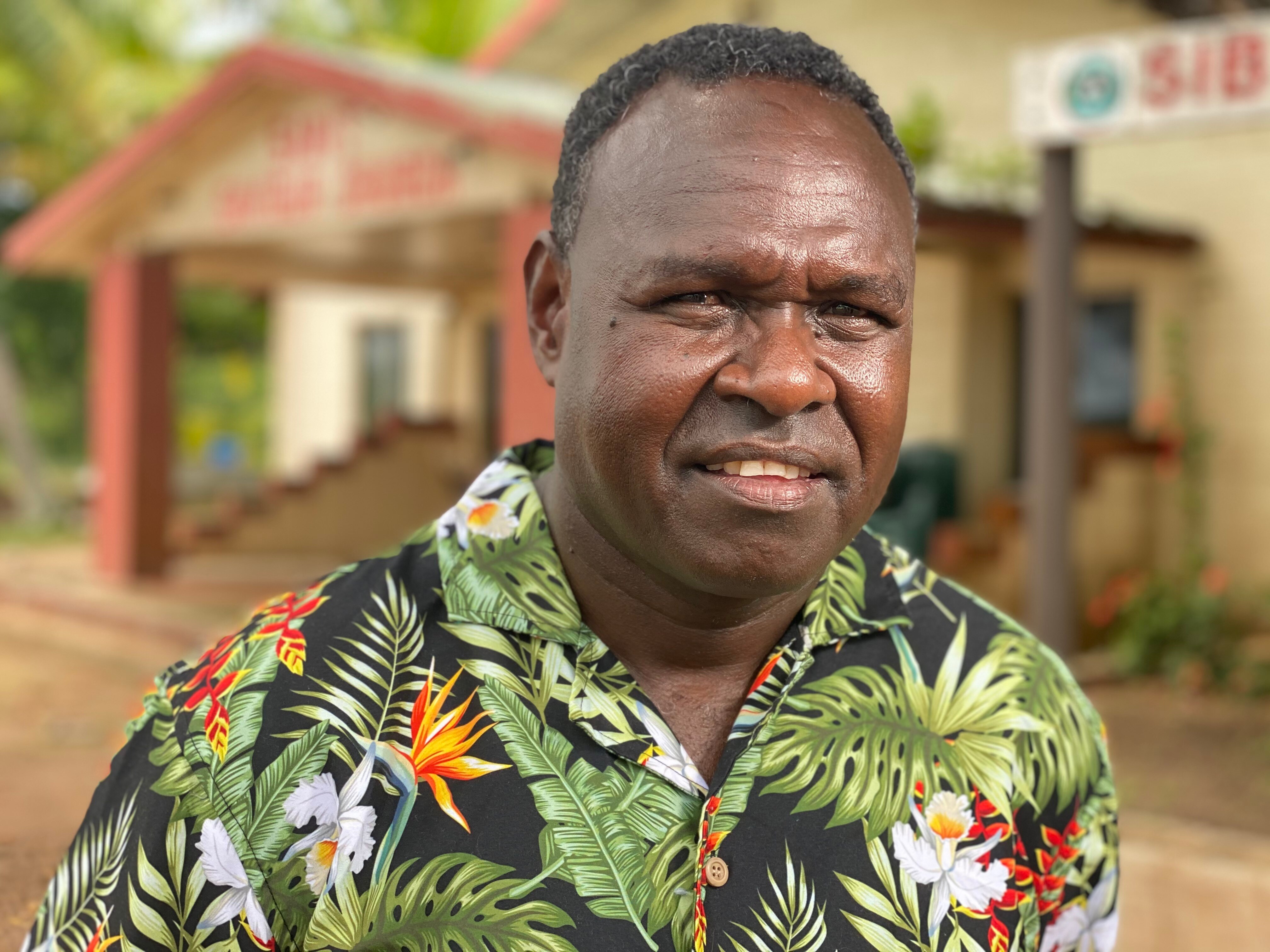 Indigenous man wearing printed shirt with leaves and flora on it. 