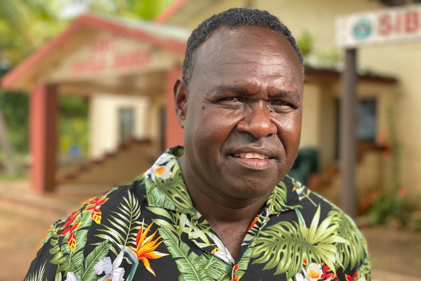 Indigenous man wearing printed shirt with leaves and flora on it. 