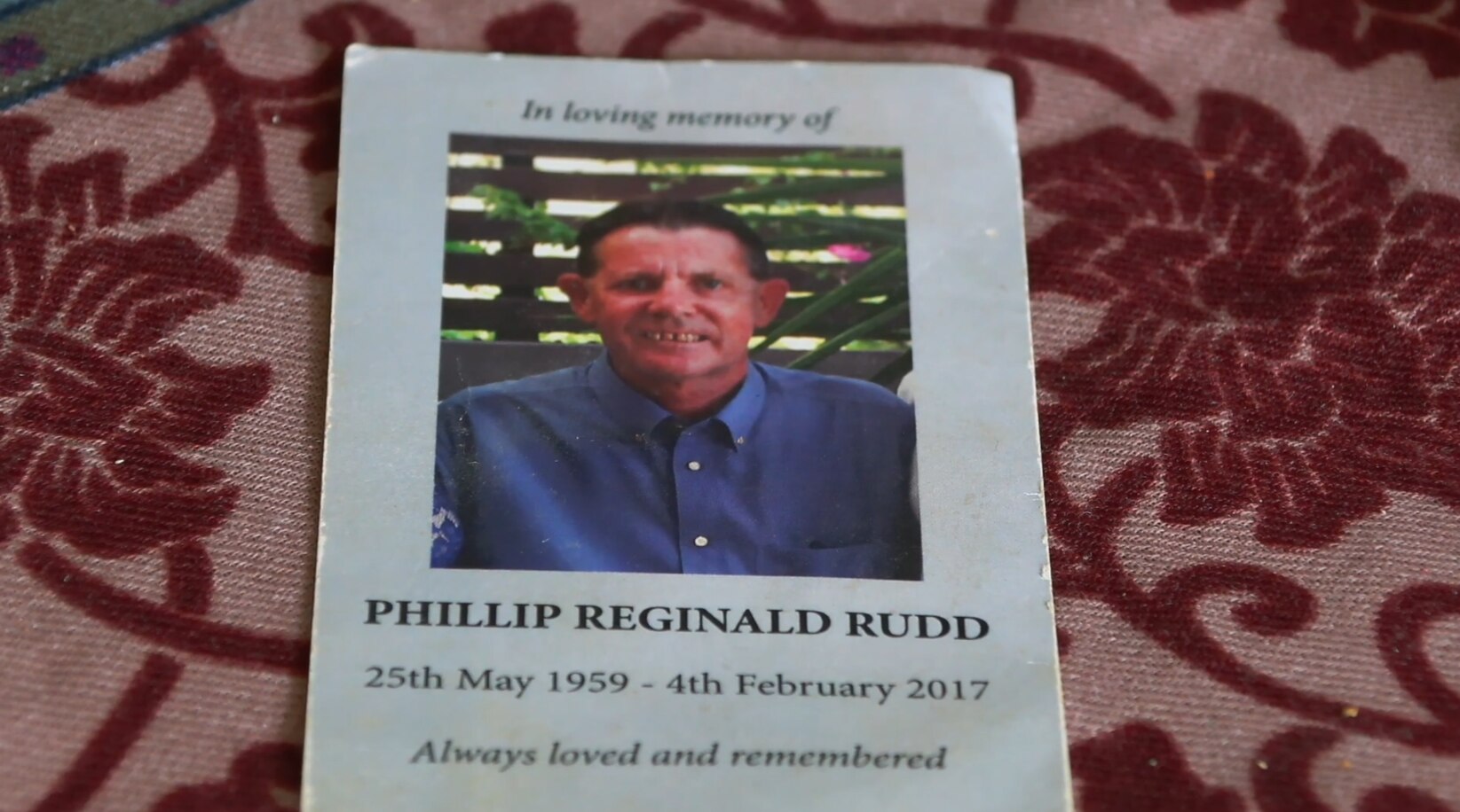 Folleto funerario con un hombre de mediana edad con camisa azul