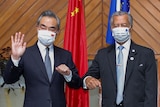 Wang Yi waves in mask and elbow bumps with Secretary General of the Pacific Island Forum Henry Puna.