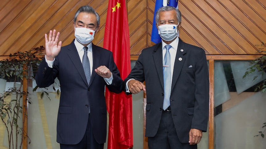 Wang Yi waves in mask and elbow bumps with Secretary General of the Pacific Island Forum Henry Puna.