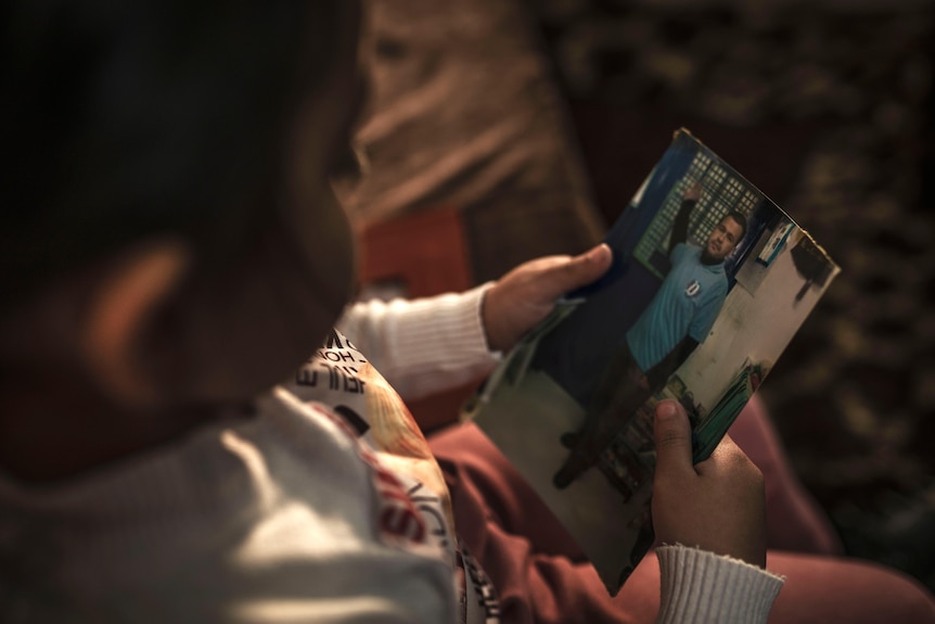 A child stares at a photo of a man wearing a blue shirt.