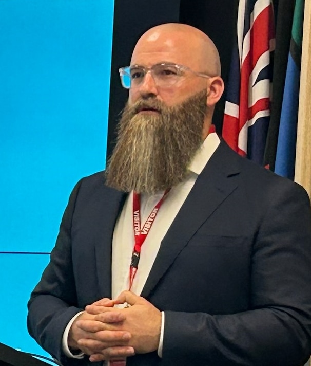 Anthony Morgan, a man with a long beard and glasses wearing a suit. 