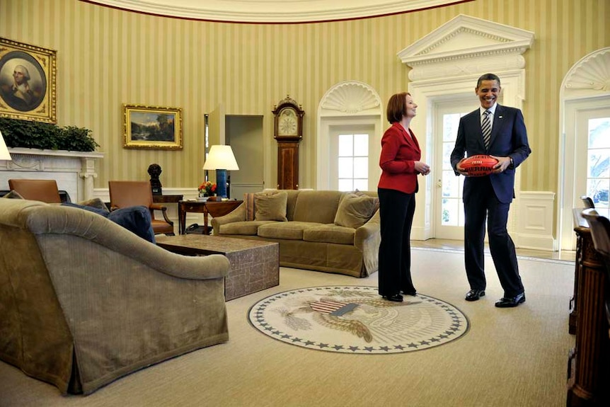 Julia Gillard shows Barack Obama an Australian Rules football in the Oval Office.