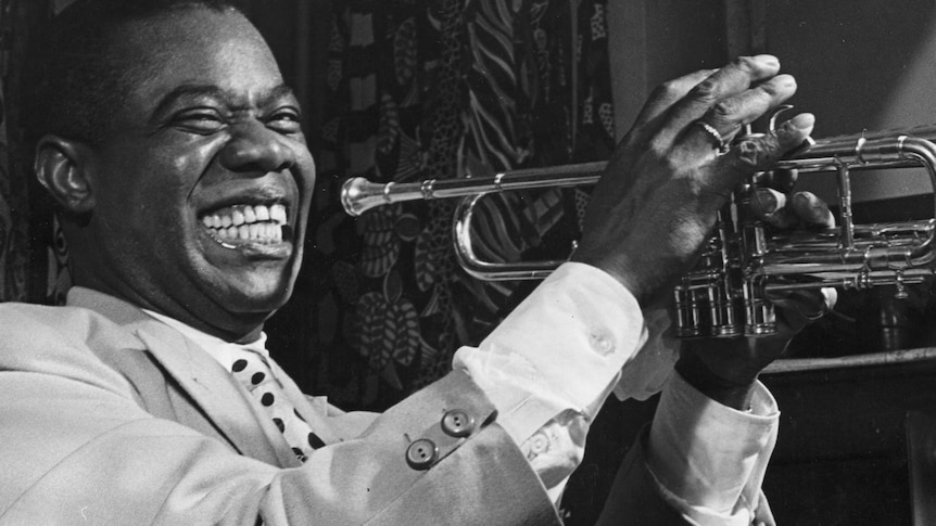 Louis Armstrong holding a trumpet and smiling