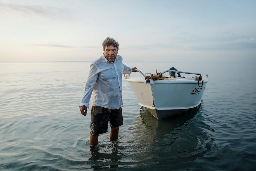 A man pulls a small boat to shore.