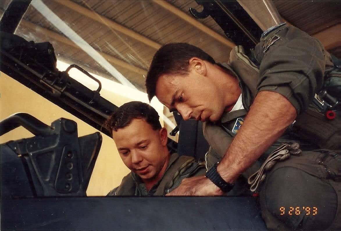 Two US Air Force men leanining over a tinkering with equipment in an aircraft.