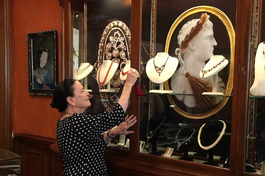 Anne Schofield with glass cabinets of her jewellery.