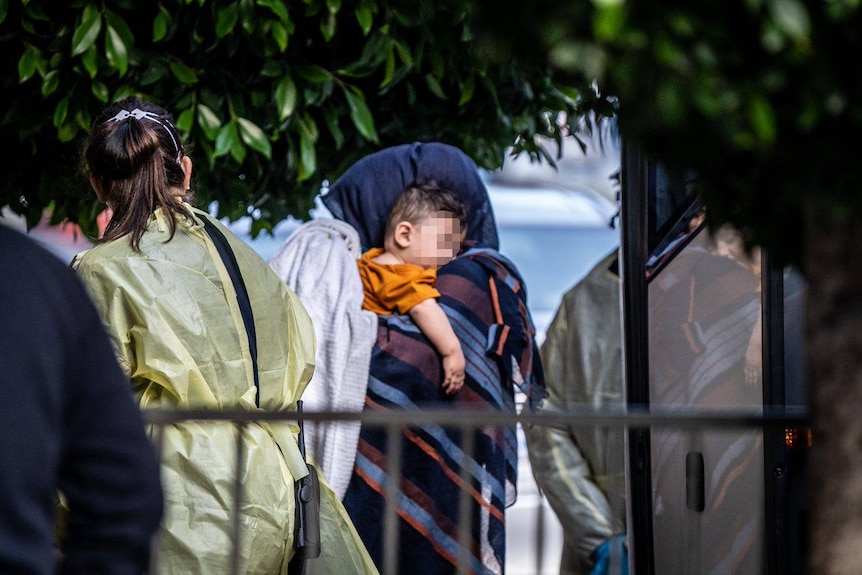 An Afghan boy sleeps on a woman's shoulder.