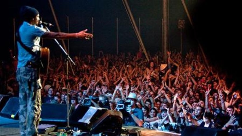 A musician on stage in front of a crowd at night