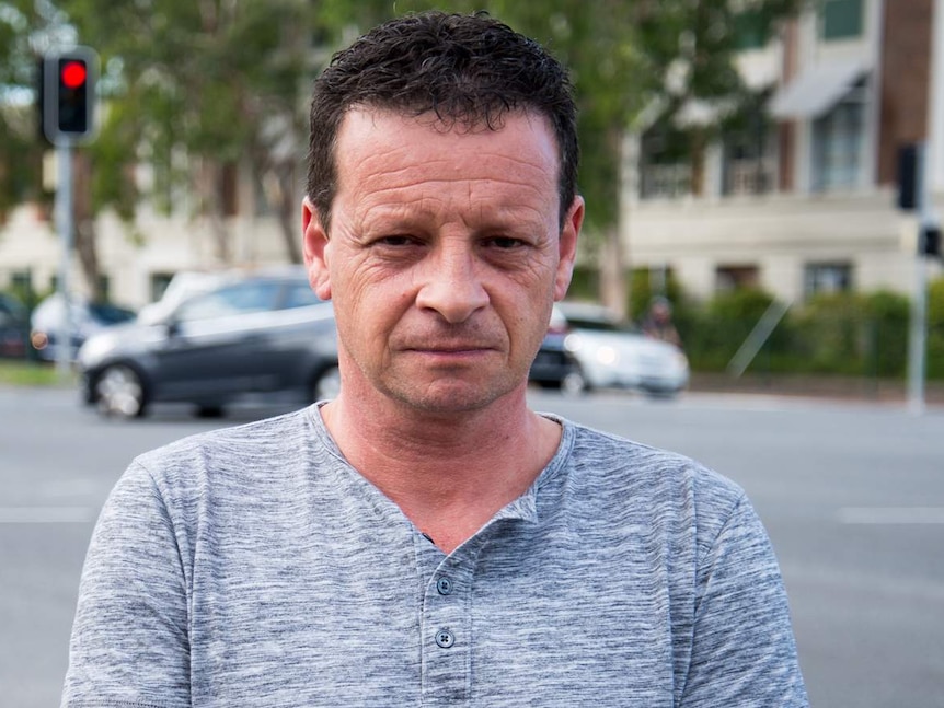 Former paramedic Chris Mawson stands, stone faced in front of an intersection.