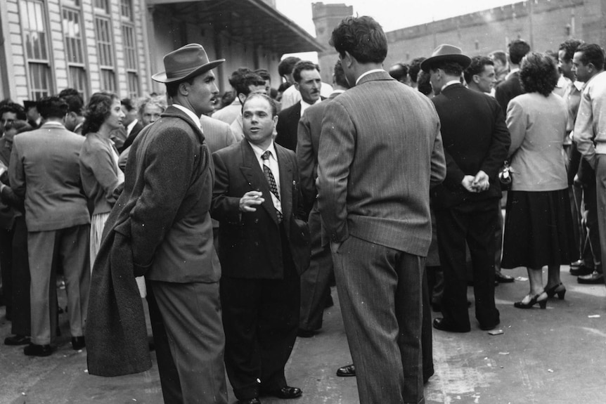 Black and white. Group of  Italian men and women standing outside talking