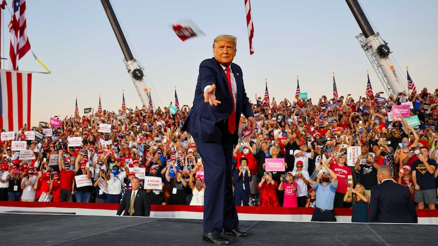 Donald Trump throws a face mask into the crowd at an outdoor rally