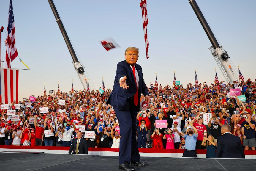 Donald Trump throws a face mask into the crowd at an outdoor rally