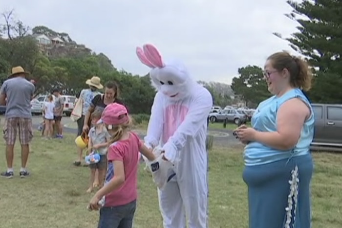 A girl stands with a person dressed as the Easter bunny