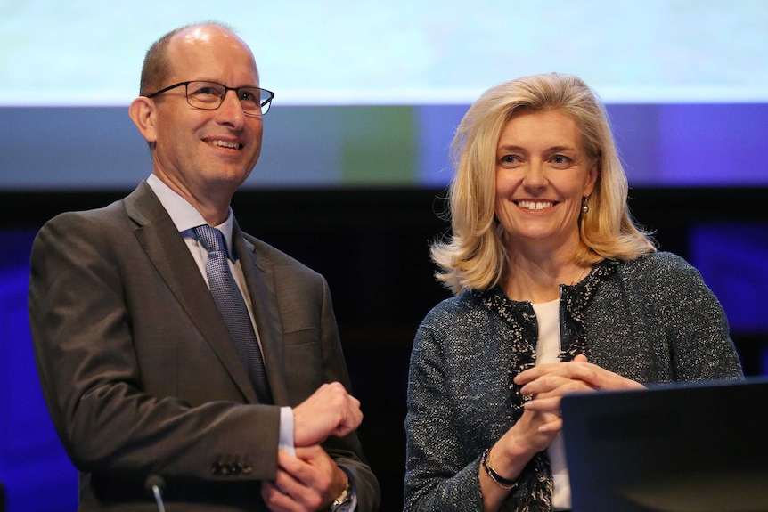 AMP CEO Craig Meller stands on stage with chairman Catherine Brenner.