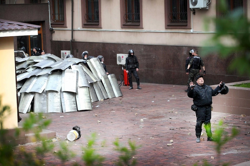 Police officers in Donetsk, Ukraine, huddle for safety under their riot shields.