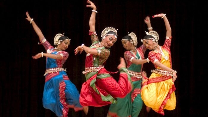 Women dancing on stage in traditional Indian costumes at the Confluence Festival of India.