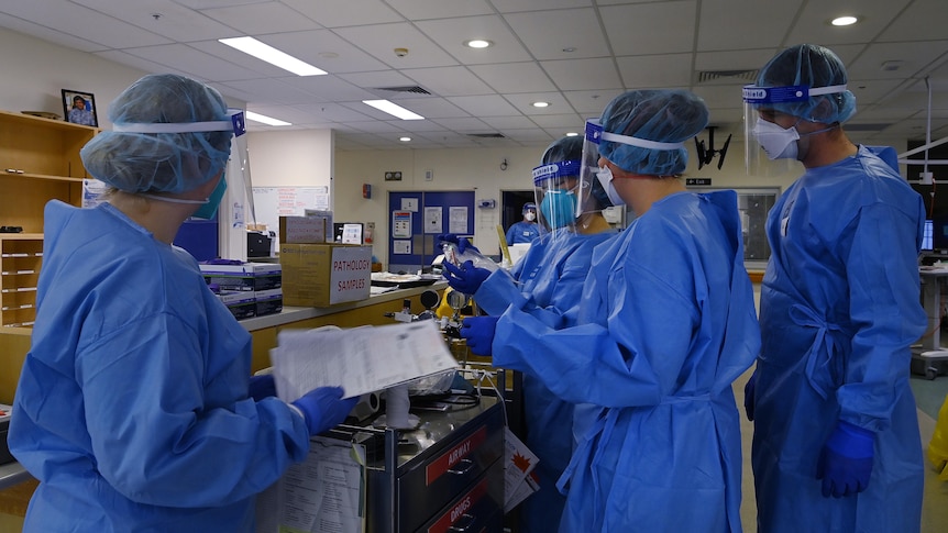 Several people dressed in PPE speaking.