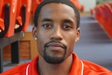 Head shot of Bryce Cotton wearing an orange top and looking straight in to the camera. 