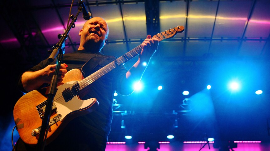 Frank Black plays guitar on a big stage 