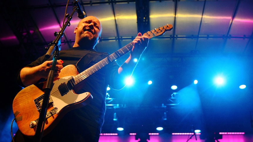 Frank Black plays guitar on a big stage 