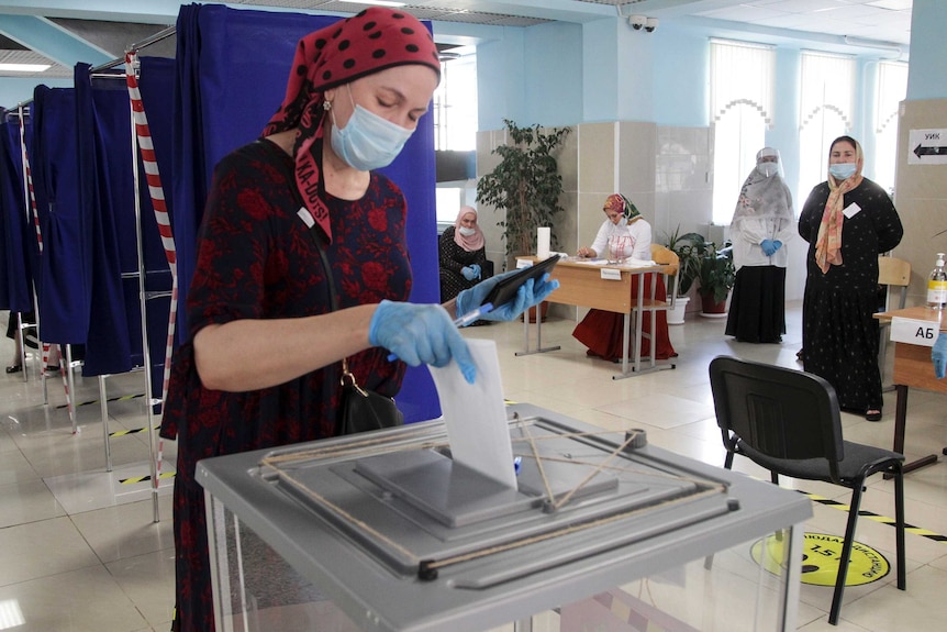 A woman in a face mask and gloves votes at a polling station in Russia.