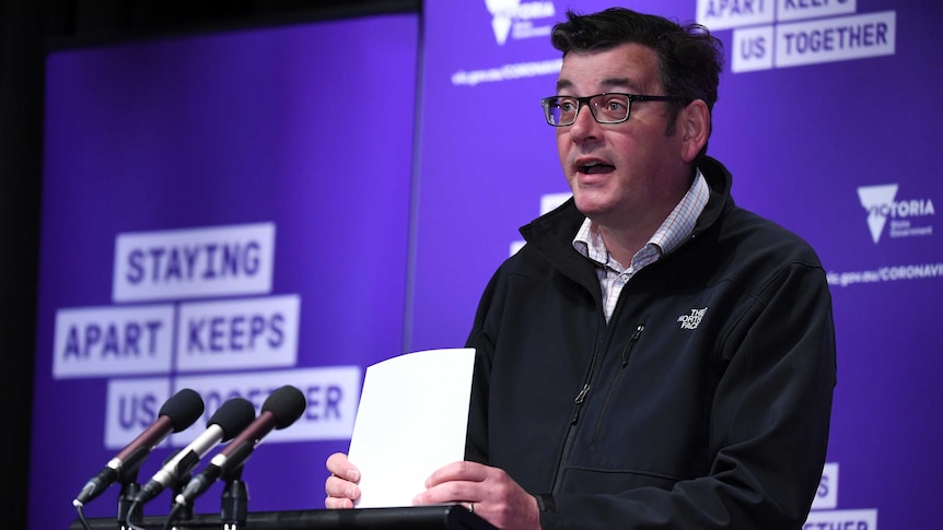 Daniel Andrews stands at the lecturn wearing a The North Face jacket during a press conference