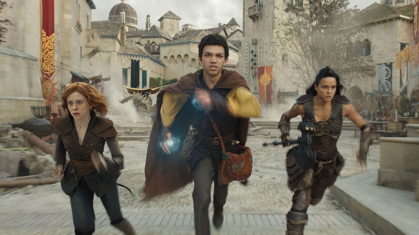 A white woman with red hair, a black young man with dark hair and a Latina woman with dark hair wear medieval garb while running