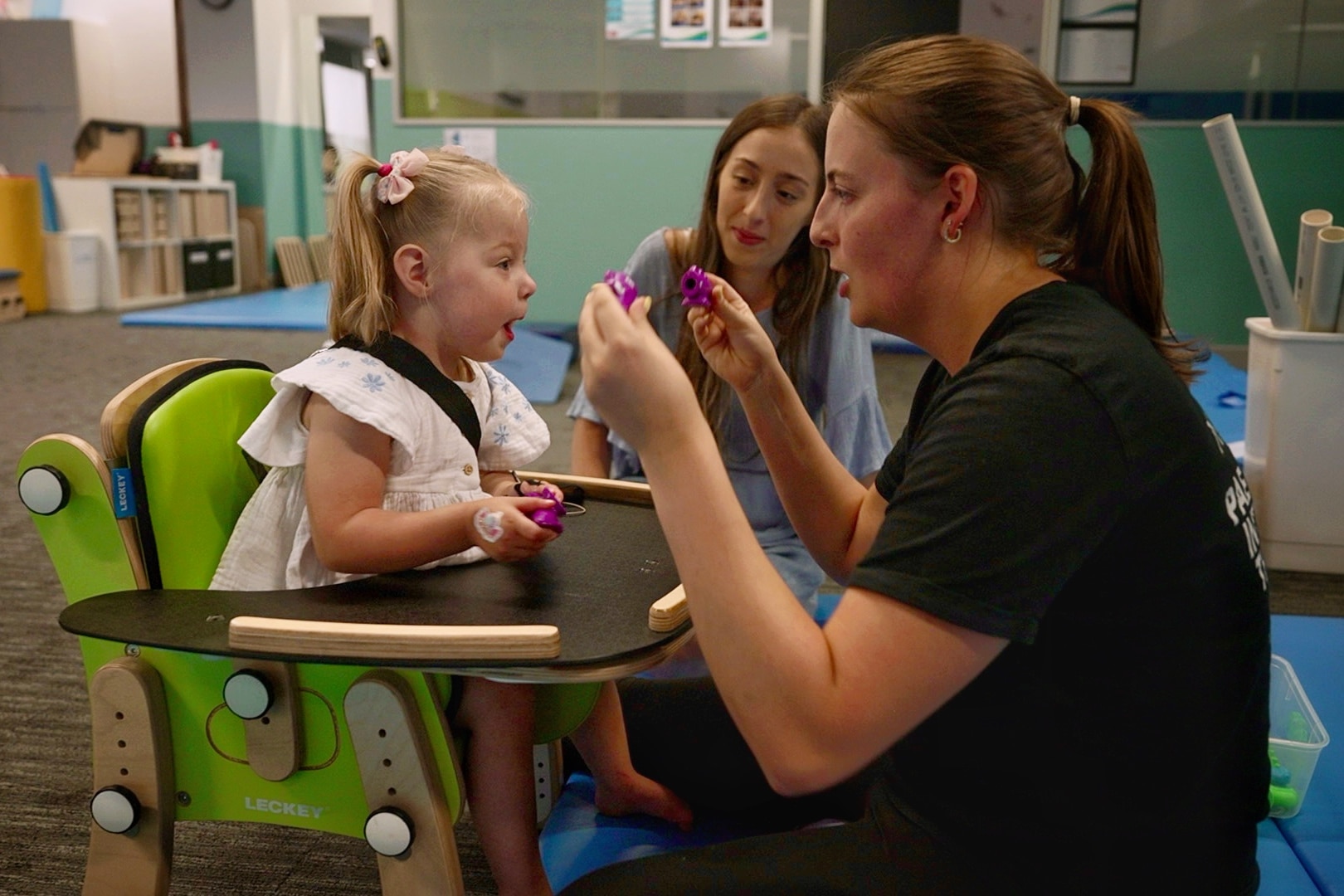 Un bebé pequeño en una silla con dos mujeres. 