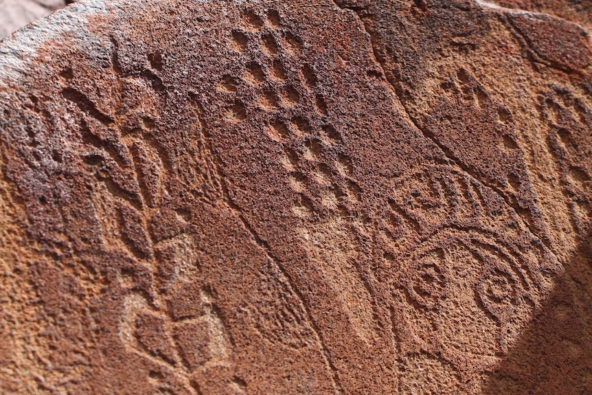 Carvings on a rock surface show intricate designs.