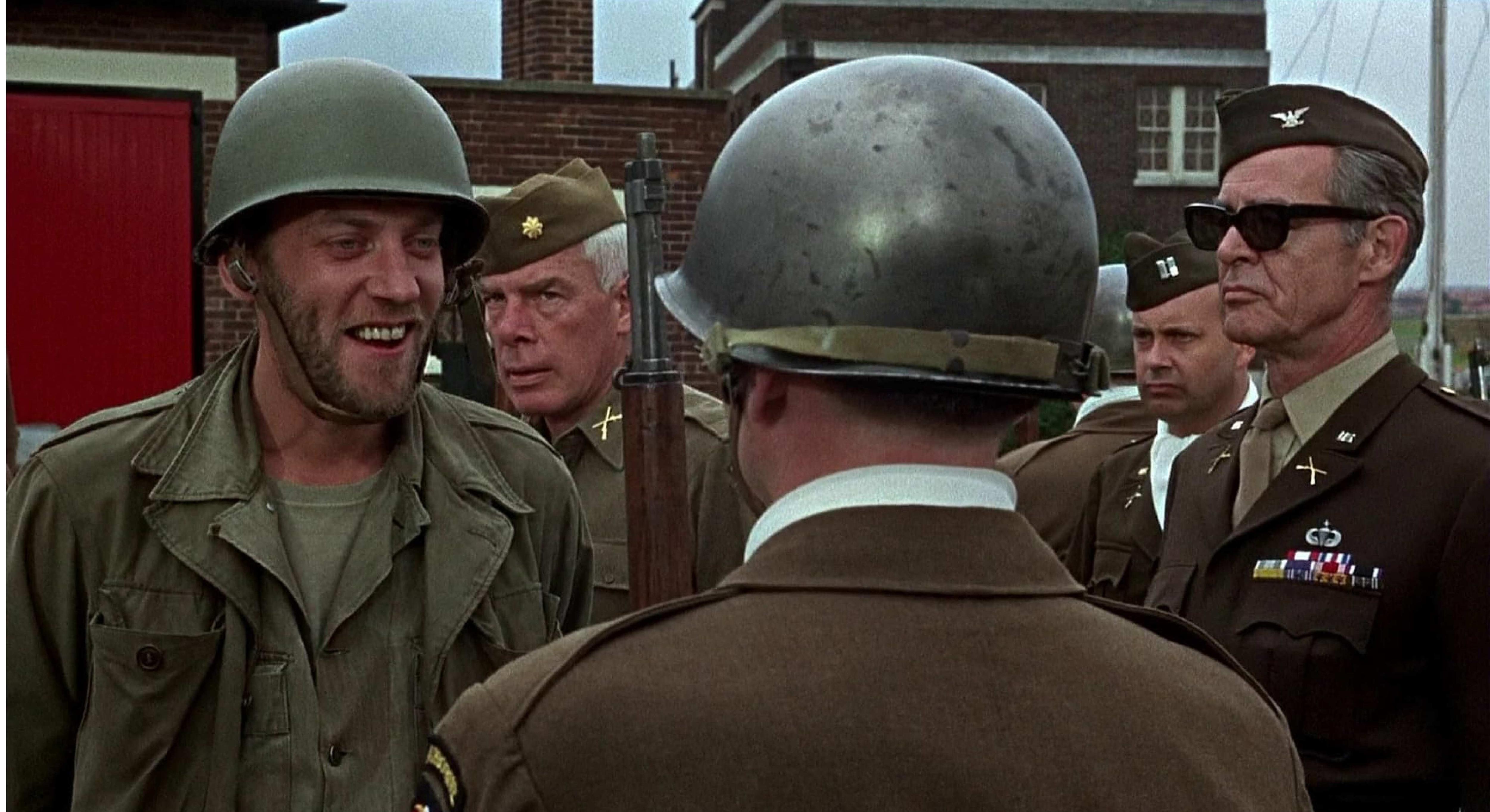 Donald Sutherland in an army outfit surrounded by commanders in the movie The Dirty Dozen