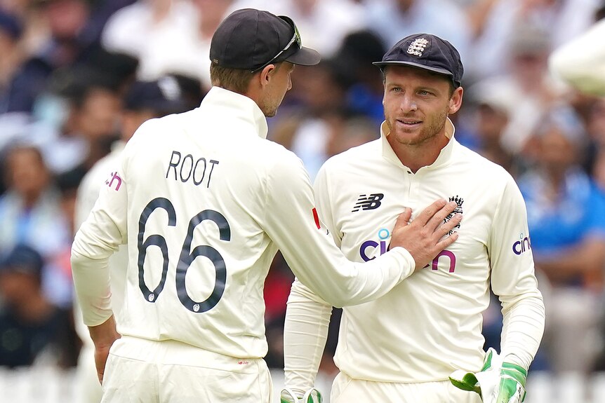 Jos Buttler walks forward as Joe Root puts his hand on his chest