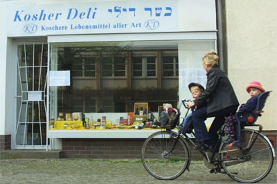 A woman rides her bike past a kosher food store in central Berlin, Germany