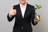 A stock image of a man in a suit holding a plant.