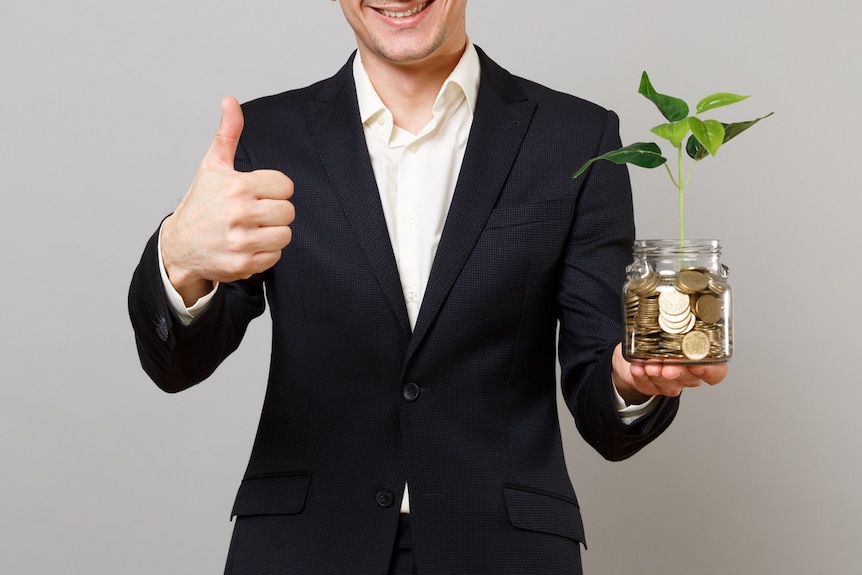 A stock image of a man in a suit holding a plant.