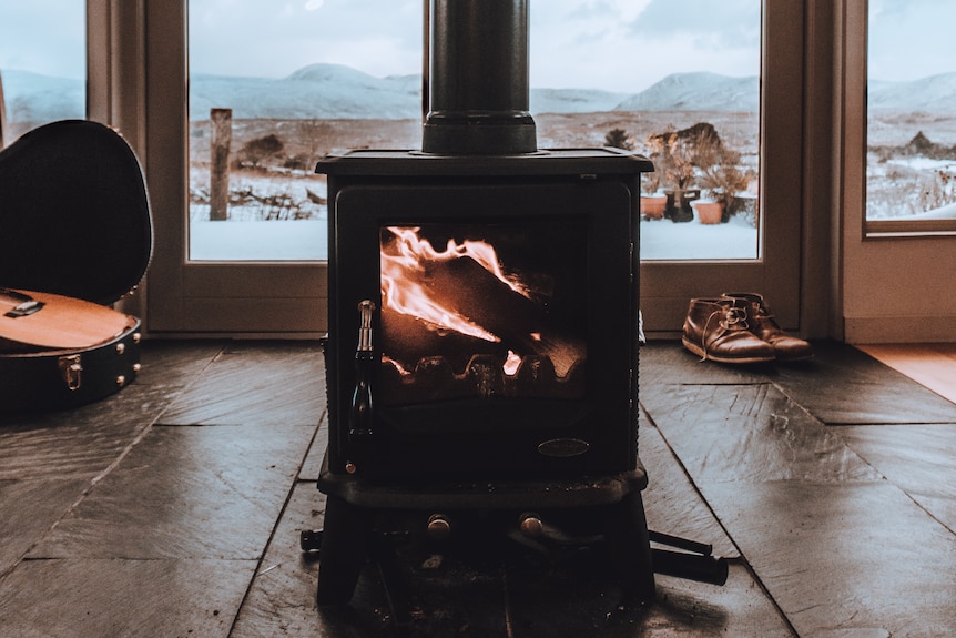 A black wood stove burns on a winter's day.