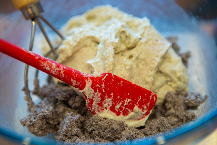 A multi-coloured bread dough being mixed in a glass bowl