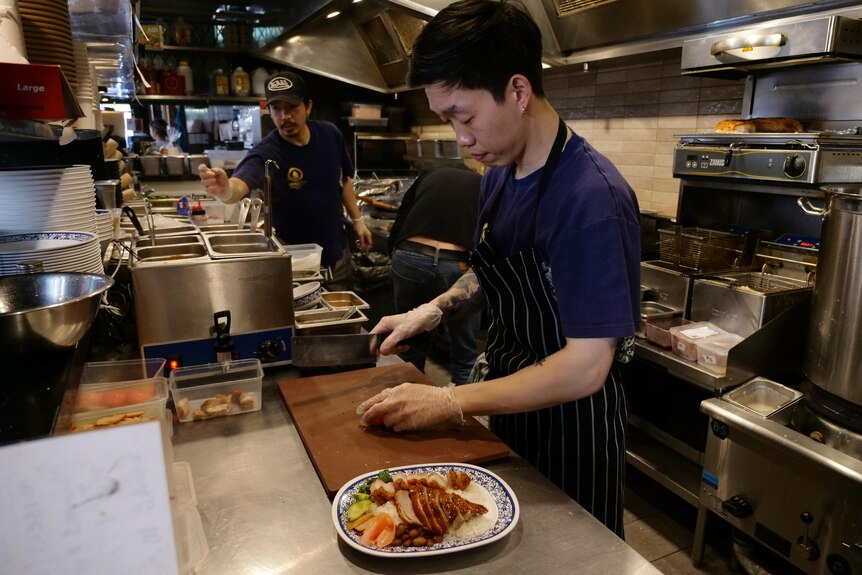 A chef cuts chicken in a restaurant kitchen
