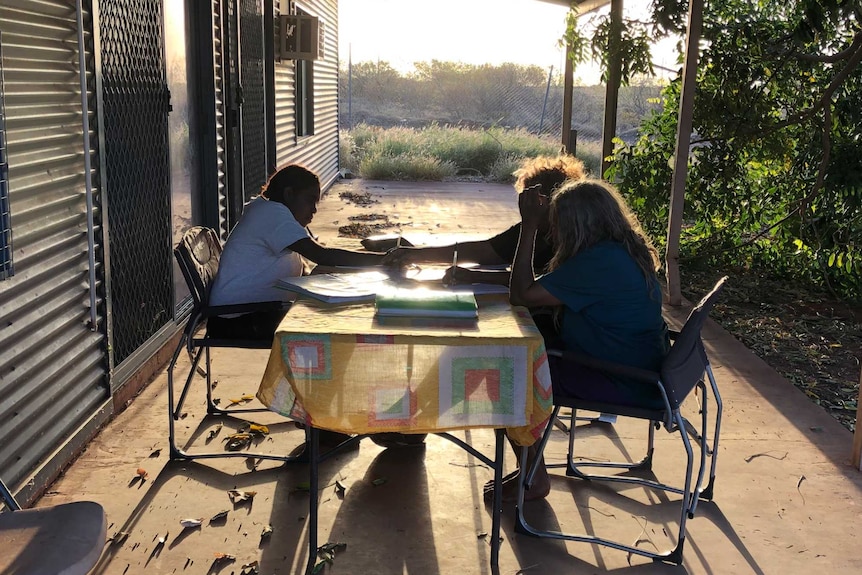 A group of young women study at a desk outside in Balgo.