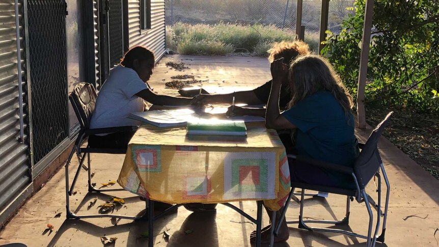 A group of young women study at a desk outside in Balgo.