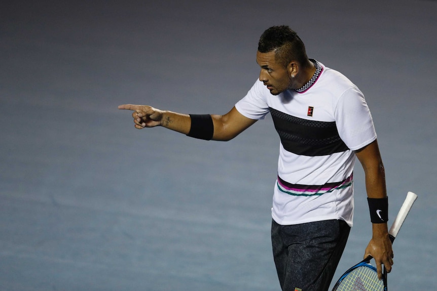 Tennis player stares down the court and points.