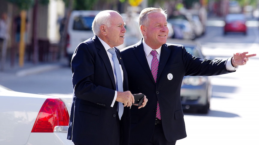 Colin Barnett on a street  points to something, John Howard leans in to look.