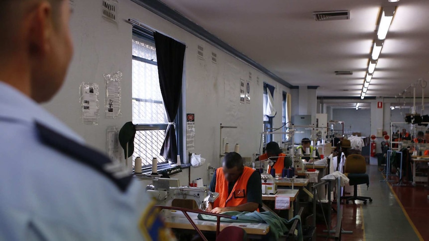 A guard watches on as the inmates make garments in the textile section.